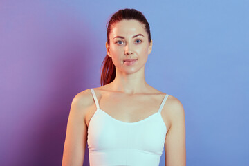 Close-up portrait of alluring woman dresses white sleeveless t shirt looking at camera with calm...