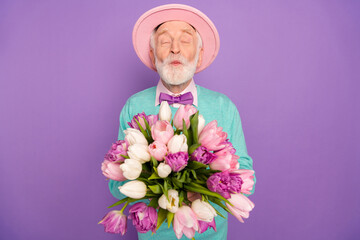 Photo of positive man closed eyes kiss lips arms hold flowers wear elegant isolated on violet color background