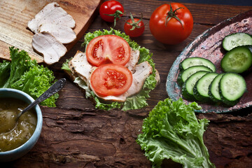 assembling sandwich with turkey meat, fresh tomatoes, cucumbers and green salad, nobody