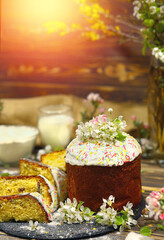 Easter sweet dessert cake. Easter cake on a dark wooden backing, ingredients. Homemade baking. The decor is apple-tree flowers. Copy space at the top. Sun rays, boke and flash background