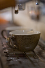 macro of espresso coffee cups in professional coffee machine with blurred backround