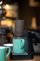 aeropress with coffee in coffee shop, closeup with background blurred