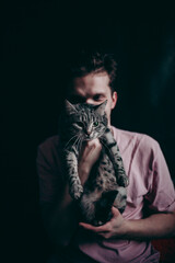 beautiful young guy with a cat on a black background