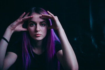 a girl with purple hair thinks on a black background