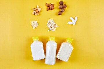 Alternative types of vegan milks in bottles on a yellow background