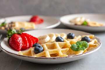 Close-up of soft Viennese waffles on the  three plates with blueberries, strawberry, chocolate sauce