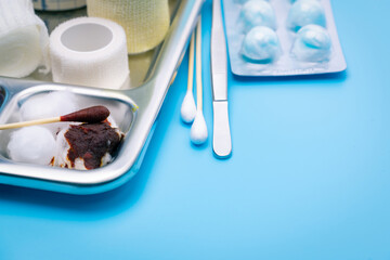 Wound care dressing set and stainless steel plate on blue background. Cotton ball and cotton stick with povidone-iodine for wounds, burns and cuts. Wound care supplies. Medical equipment for nurse.