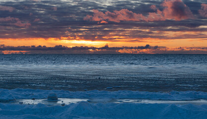 Obraz premium Beautiful winter cloudy sunset over Baltic sea. The sea covered with ice. Natural background. Latvia. Copy space for text.