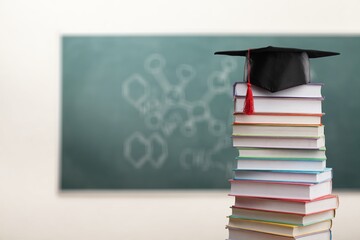 Stack school books with a black graduation hat