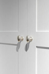 Furniture fittings. Metallic silver door handles with sharp shadows on the white facade