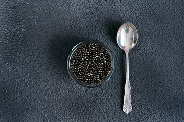 Black fish caviar on a black background.