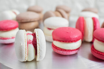 Close up of colorful white, red, and caramel chocolate macarons dessert, filling with tasty ganache, on the table at light kitchen or confectionery shop