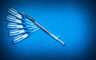 Medical syringe with ampoules on a blue textured background.