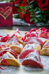 Colorful hamantaschen cookies with love card and flowers. Jewish traditional pastry for Purim (Jewish carnival holiday with celebration concept). Homemade gluten free cookie filled with chocolate