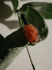 Pendants made of natural sun stone lie on a white background next to eucalyptus leaves
