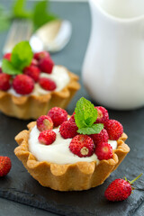Wild strawberry tartlets with cream filling. delicious summer fruit mini tarts