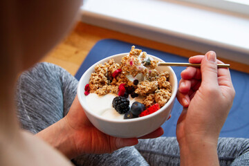 Unrecognizable woman eating granola bowl