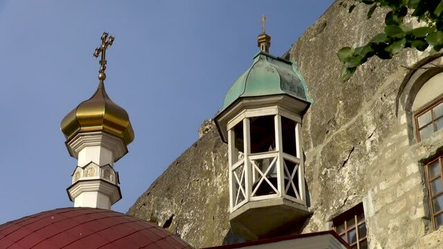 Crimea, Sevastopol. Dome of main cathedral acting cave monastery of St. Klimento. St. Inkerman. Golden dome with golden orthodox cross in rays of evening sun at sunset. 