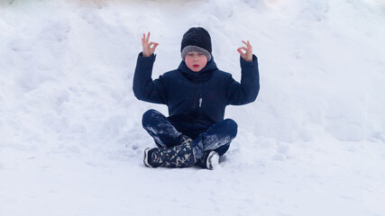Fototapeta na wymiar A teenage boy sits in the winter snow in a yoga pose and meditates