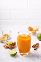 Healthy drink from turmeric and ginger roots and lime in a glass on white concrete background.