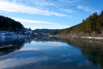 Wide-angle lens shot of a lake under a sunny blue sky in winter