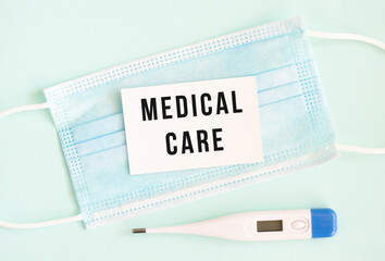 White card with the inscription MEDICAL CARE on a medical protective mask.