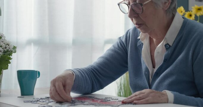 Elderly woman playing puzzle at home