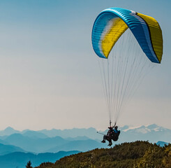 Beautiful alpine summer view with a paraglider and mountain silhouettes in the background at the...