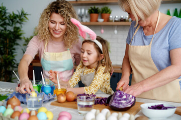 Fototapeta premium Three generations of women making Easter eggs