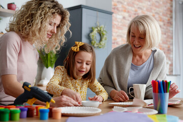 Three generations of women making handmade Easter decorations