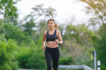 Obraz na płótnie Canvas Woman Runner with black sport wear run in the green jungle.