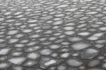 The process of ice melting, when a large number of small round white ice floes float on the surface of a dark water reservoir