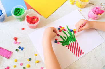 Child making homemade greeting card. little girl making vase with flowers from paper and clay, plasticine as gift for Mothers day, Birthday or Valentines day . Arts  crafts concept.