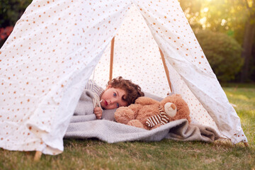 Young Boy Having Fun Inside Tent Or Tepee Pitched In Garden