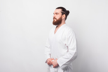 Side view portrait of serious bearded man in taekwondo uniform.