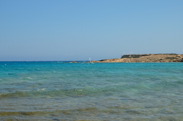 Sand, turquoise sea water, and blue Cycladic sky