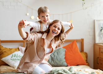 Woman playing with boy on bed