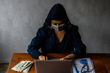 Asian hacker woman with surgical facemask typing on laptop notebook