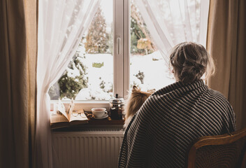 Old retired woman (senior) by the home window - retirement concept