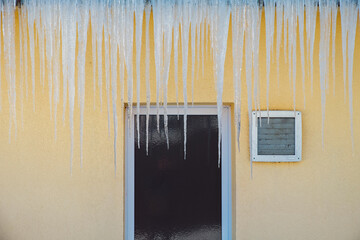 gefährliche Eiszapfen an Haus und Dachrinne im Winter gefroren zu Eis