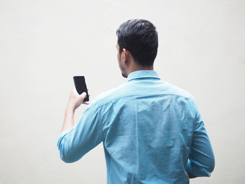 Back View Of A Man Using Mobile Phone Wearing Blue Shirt