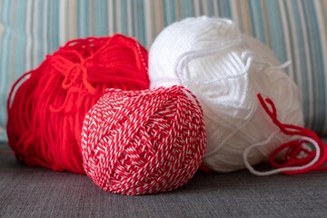 Close up red and white yarn strains coiled in ball skein for making martenitsa - bulgarian folklore tradition in March. Shallow depth of focus. Baba Marta day.
