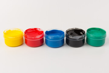 Plastic jars with paint of different colors for children's creativity on white background. Paint...