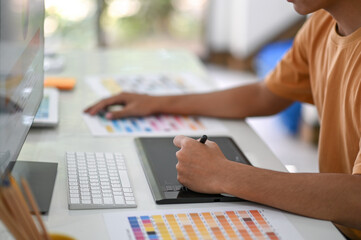 Professional graphic designers are working on digital boards with color charts on their desk.