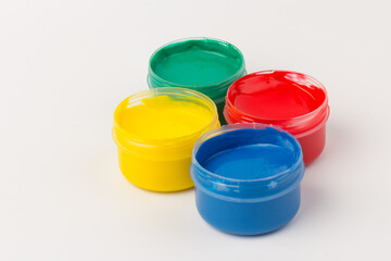 Plastic jars with paint of different colors for children's creativity on white background. Paint...