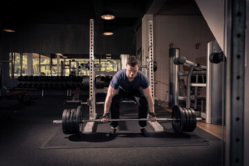 Obraz na płótnie Canvas male athlete is lifting a barbell in a fitness center, doing his daily workout