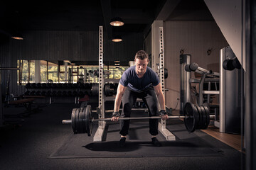 male athlete is lifting a barbell in a fitness center, doing his daily workout