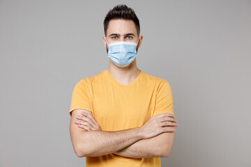 Young caucasian man 20s in yellow basic t-shirt in sterile face mask to safe from coronavirus virus...