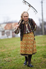 Old farmer woman cleaning with a rake