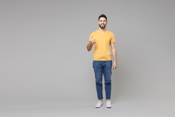 Full length young caucasian serious bearded attractive handsome man 20s wear casual yellow basic...